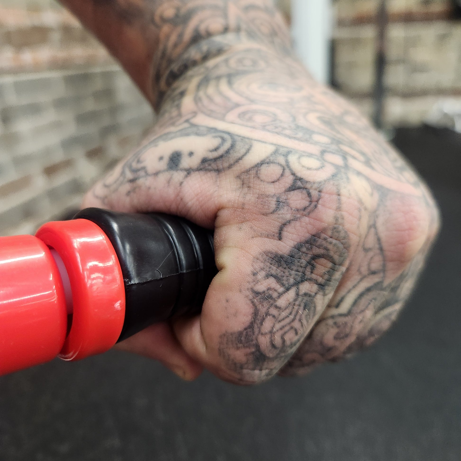 A close-up of a person’s hand gripping the Reflex Flexible Massage Stick’s handle, highlighting the textured grip for secure handling.