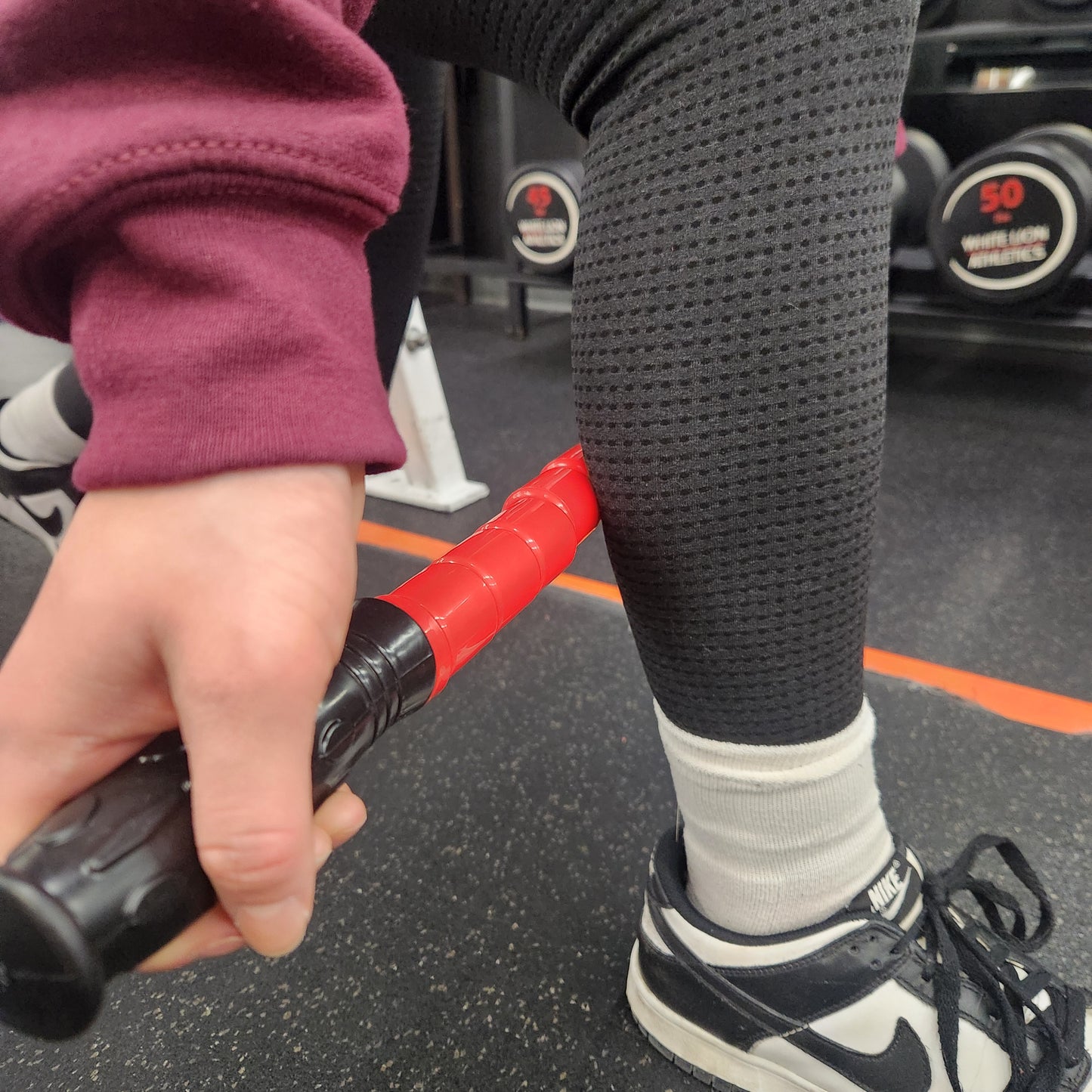 A person applying the Reflex Flexible Massage Stick to their lower leg while seated, demonstrating its effectiveness for relieving muscle tension.